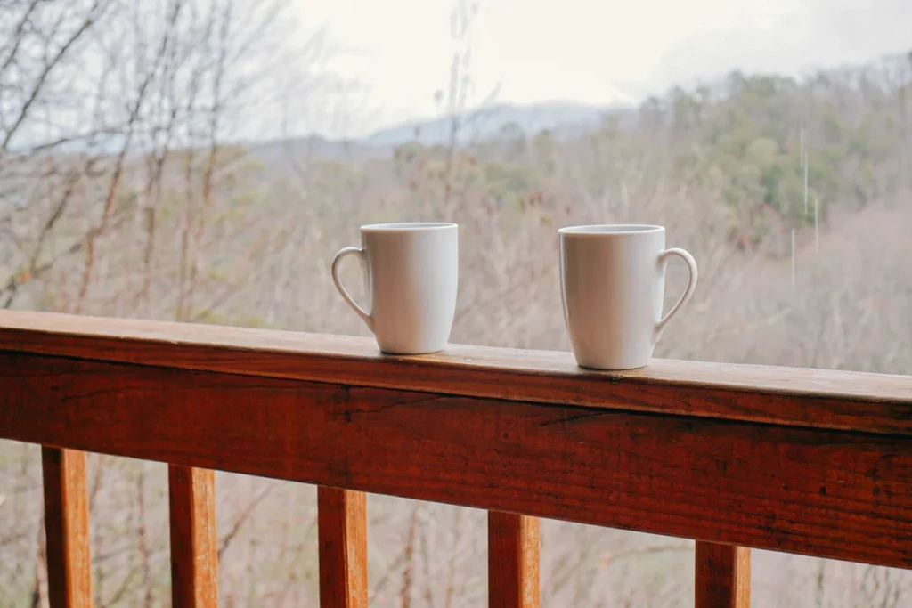 Two coffee mugs on a cabin deck rail overlooking a misty Smoky Mountain ridge near Pigeon Forge