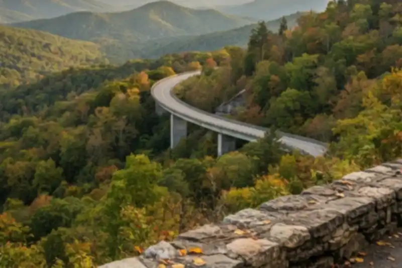 Autumn view from a stone overlook on the Foothills Parkway with a curving road below and layered Smoky Mountain ridges