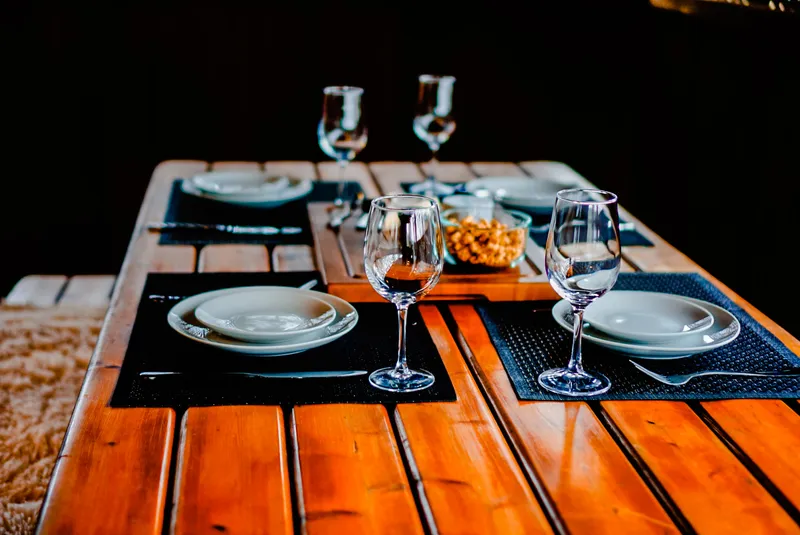 Screened-porch picnic table set for dinner with wine glasses