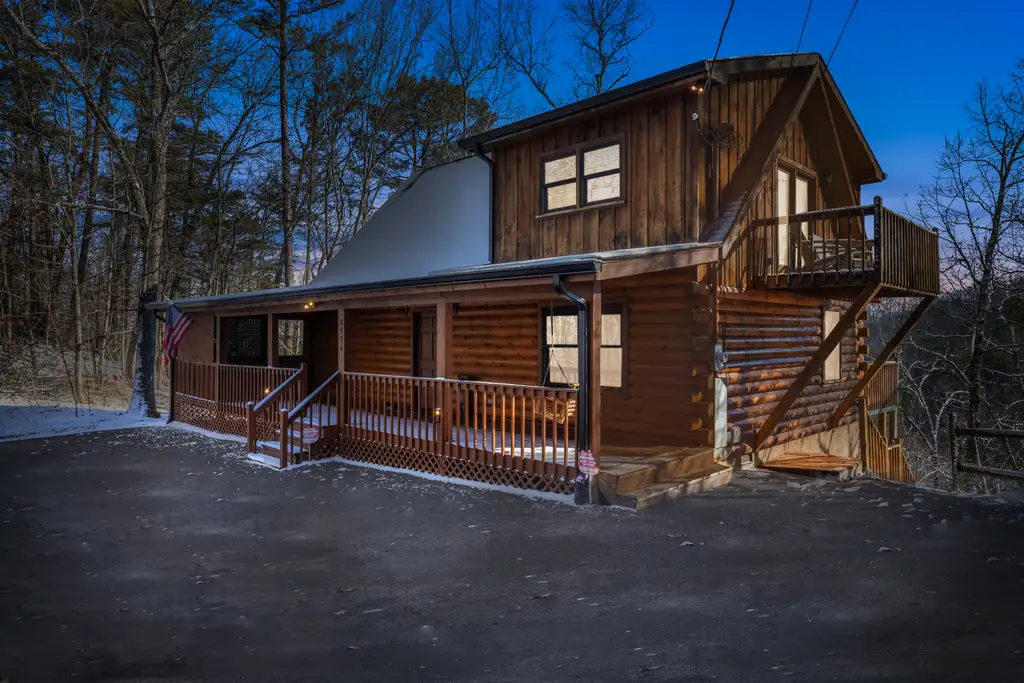 Sunny Sierra Cabin — log cabin near Pigeon Forge glowing at dusk with a dusting of snow